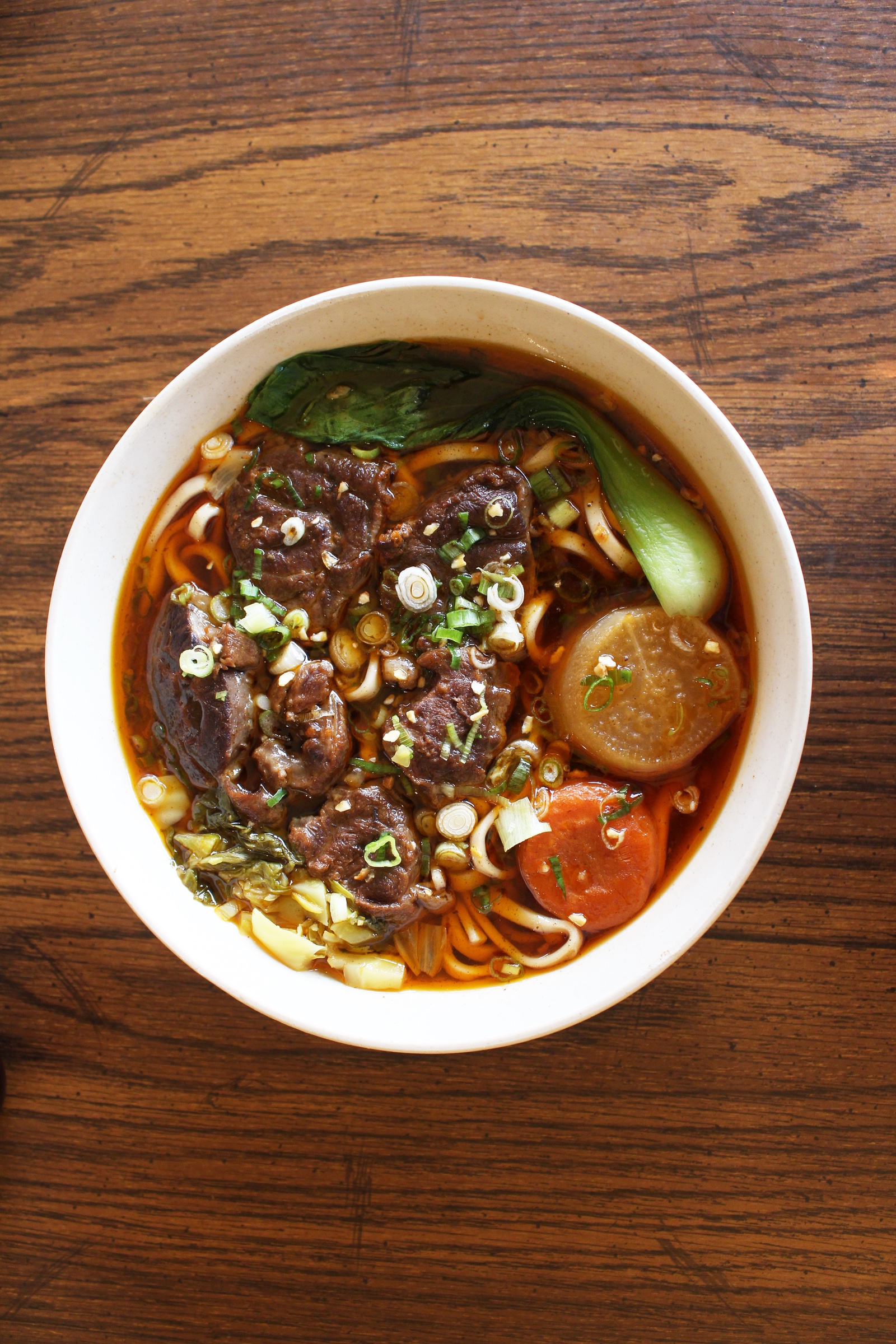 Formosa beef noodle soup topped with scallions and greens