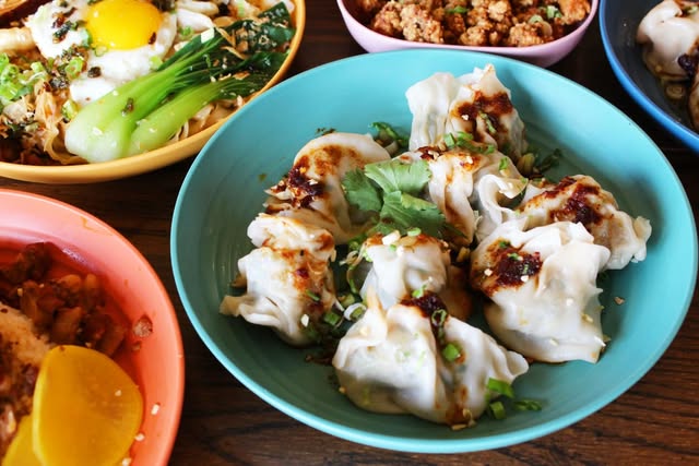 Formosa dumplings with chili sauce and cilantro, served on a blue plate