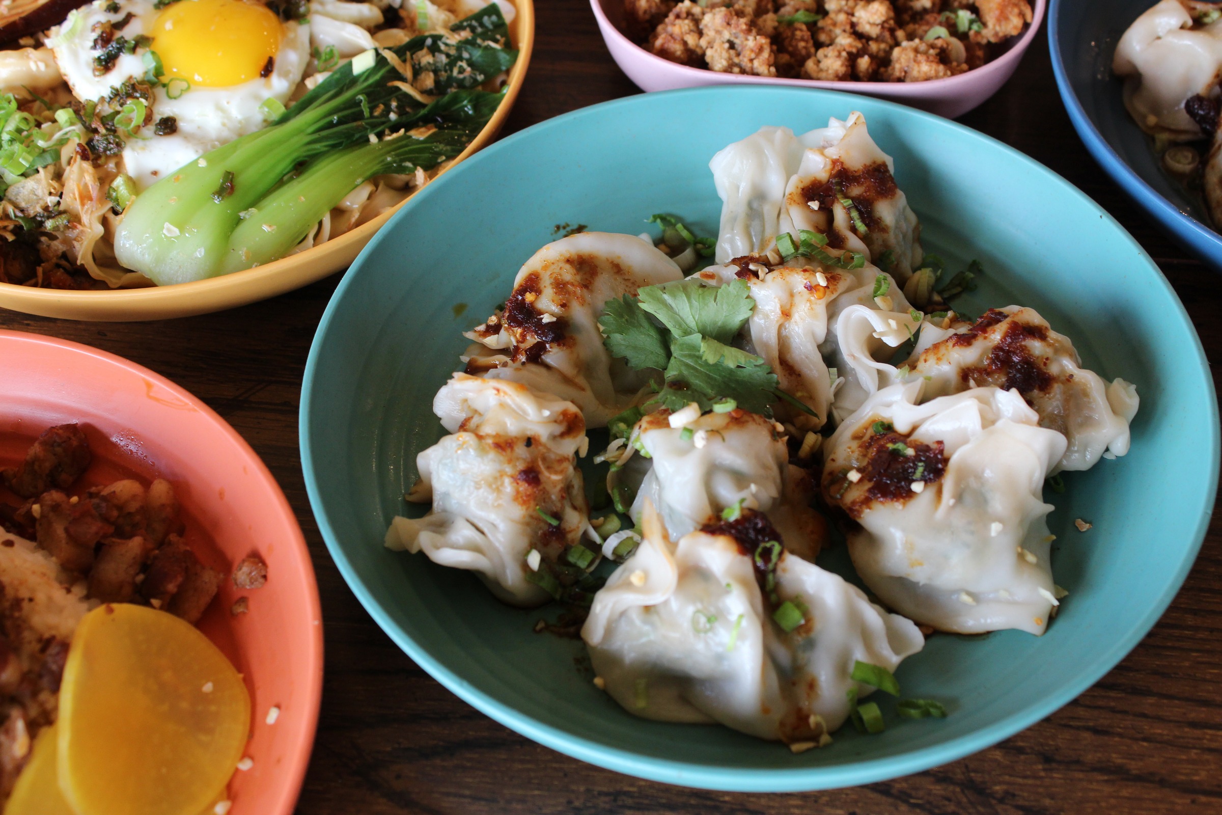 Formosa handmade dumplings with chili sauce and cilantro, surrounded by Taiwanese comfort dishes